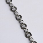 Close-up of a handmade stainless steel chainmail bracelet showing the detailed Helm weave pattern with interlocking large and small rings.