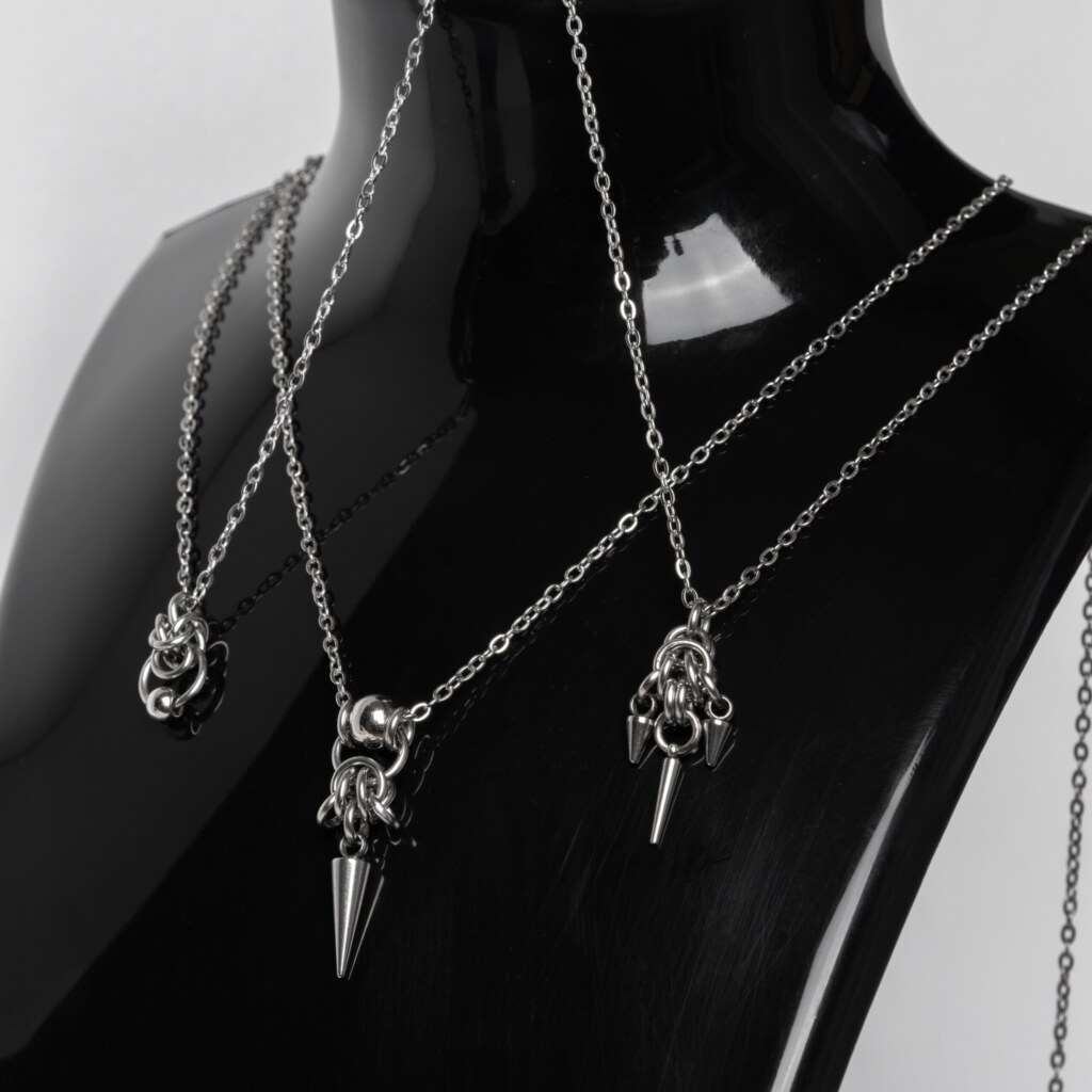 Three handmade stainless steel minimalist necklaces with fine chain and small pendants — triple spike, bead with long spike, and bead with ring — displayed against a white background.