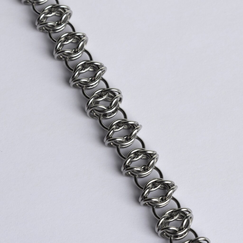 Close-up of a handmade stainless steel chainmail bracelet showing an open weave pattern with repeating oval ring formations.