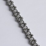 Close-up of a handmade stainless steel chainmail bracelet showing an open weave pattern with repeating oval ring formations.