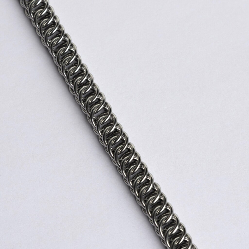 Close-up of a handmade stainless steel chainmail bracelet showing a diagonal scale pattern in a Half Persian weave with overlapping interlocked rings.