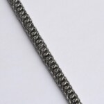 Close-up of a handmade stainless steel chainmail bracelet showing a diagonal scale pattern in a Half Persian weave with overlapping interlocked rings.