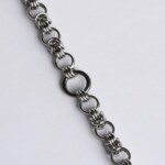Close-up of a handmade stainless steel chainmail bracelet showing the intricate Byzantine weave pattern with woven link units connected by single open rings.